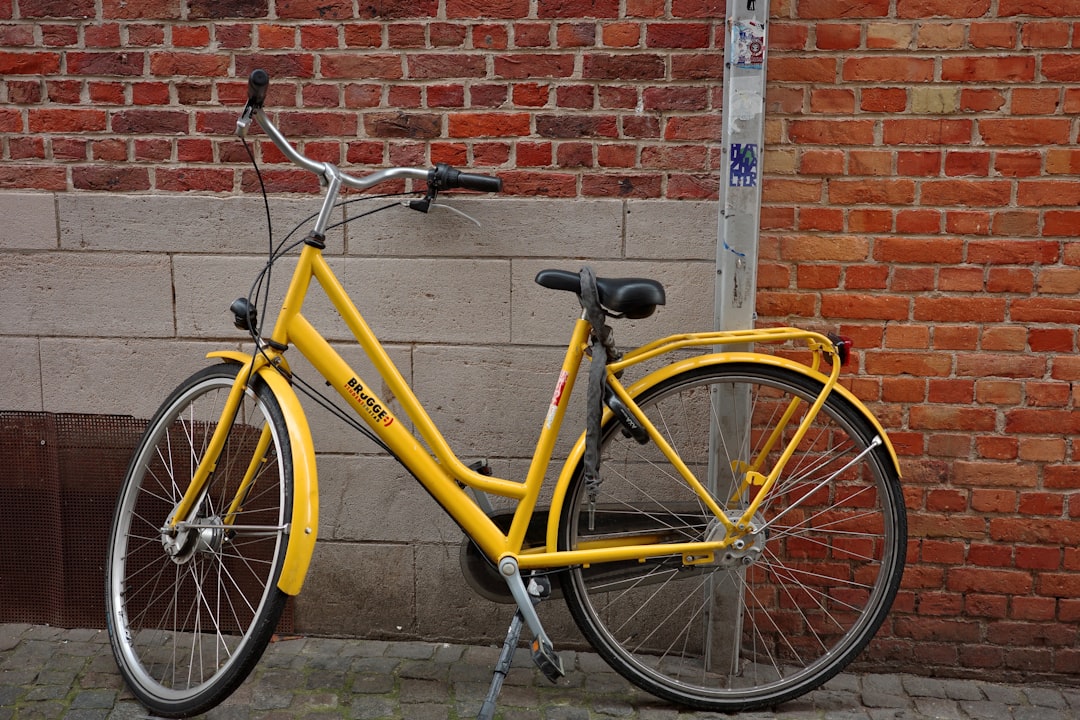 A yellow bicycle leans against a brick wall.