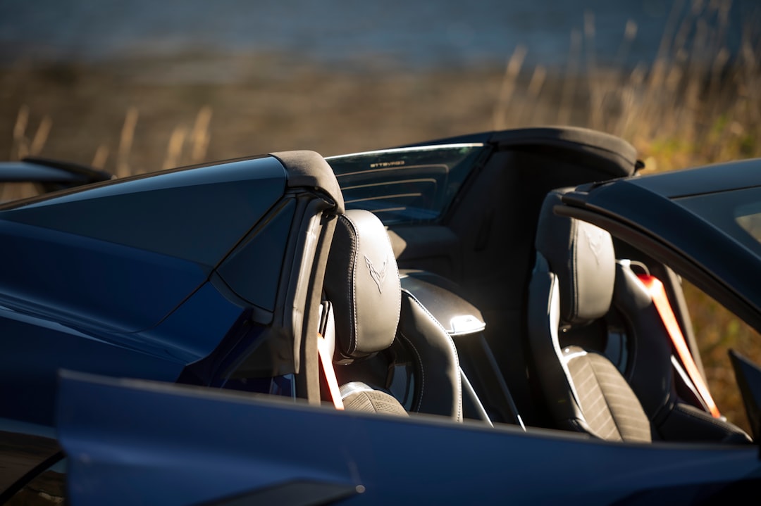 Two seats in a dark blue convertible sports car.