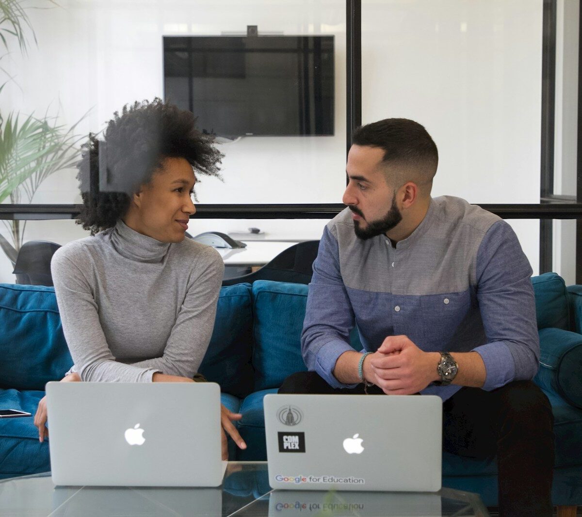 a man and a woman sitting on a couch with laptops