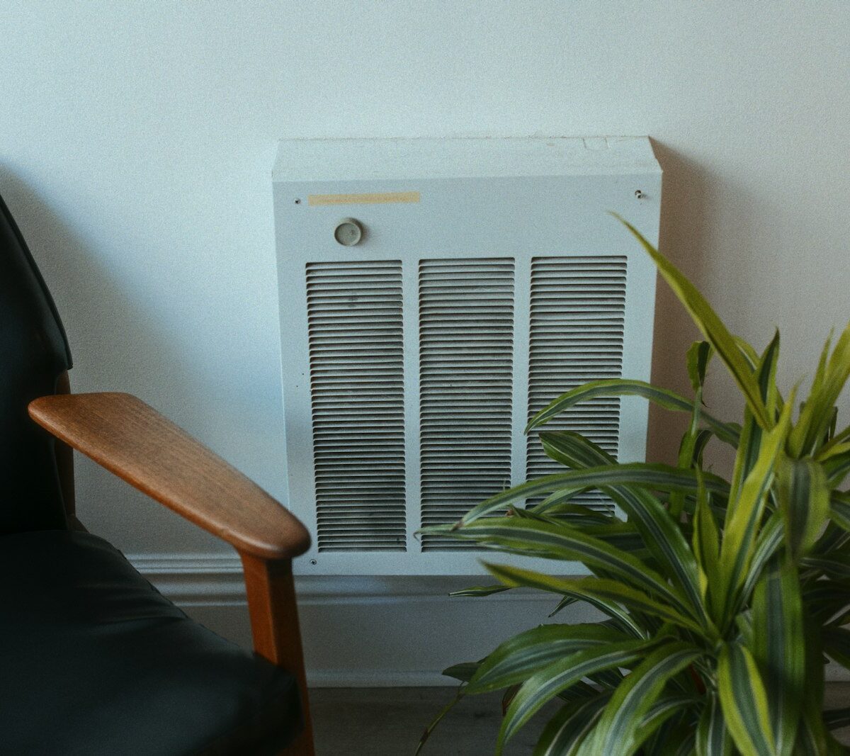 Vrijstaande elektrische verwarmingszuil (thermozuil) naast een stoel in een woonkamer