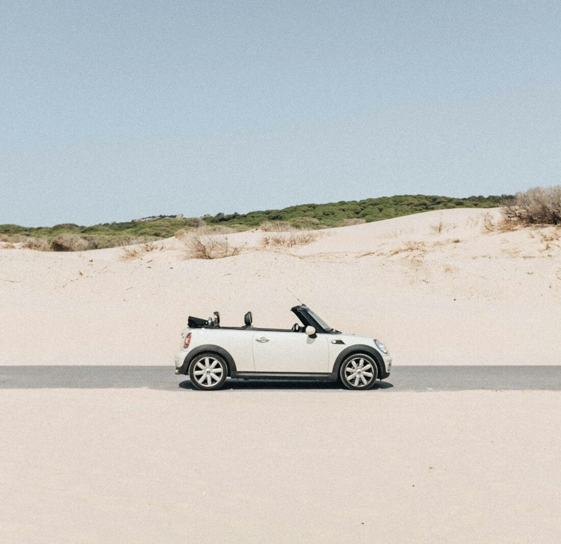 Kleine zilvergrijze cabriolet met open dak geparkeerd langs een zonnige weg