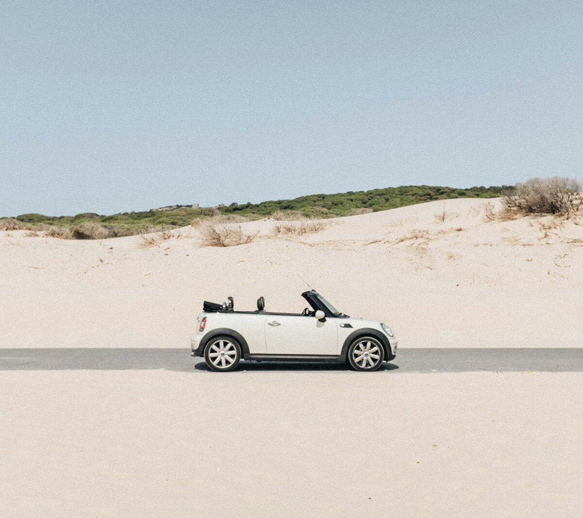 Kleine zilvergrijze cabriolet met open dak geparkeerd langs een zonnige weg