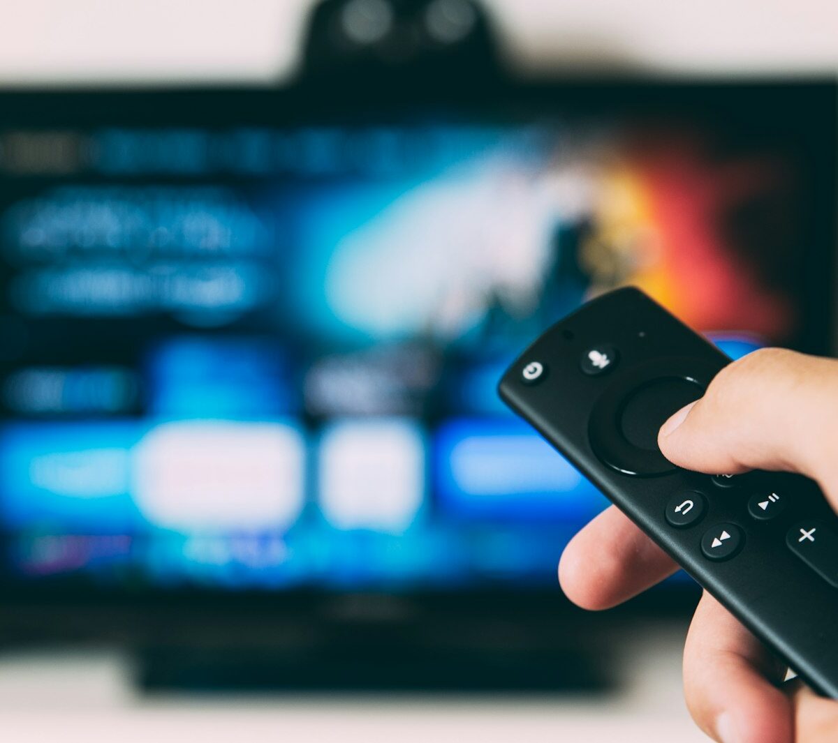 Hand met afstandsbediening voor een televisie in de woonkamer