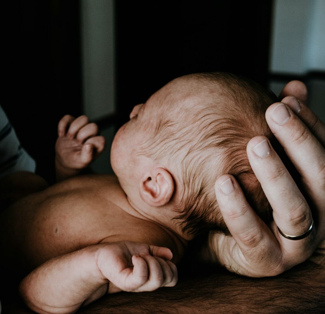 Jonge vader houdt zijn pasgeboren baby vast in de woonkamer