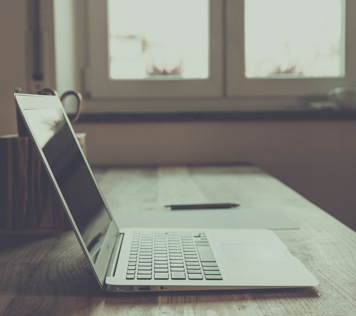 Laptop met een factuur op het scherm naast een notitieblok op een bureau