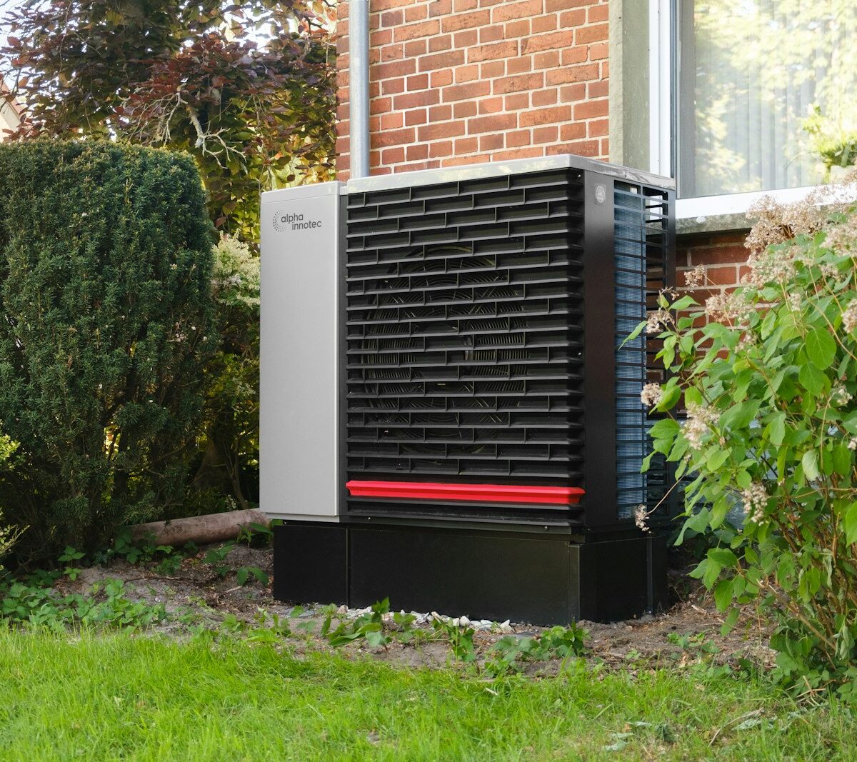 Buitenunit van een warmtepomp tegen de gevel van een woning