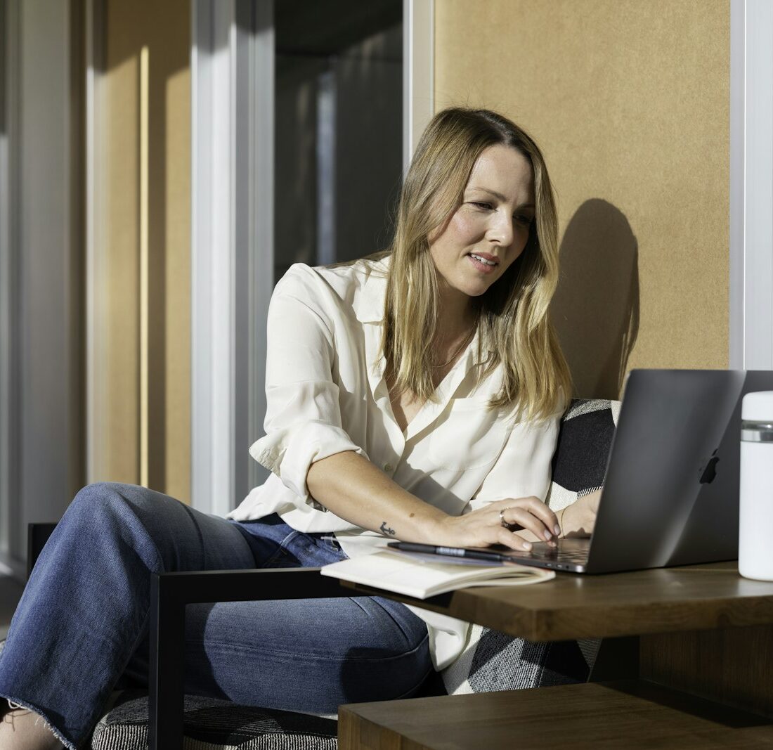 Jonge vrouw doet haar belastingaangifte op een laptop aan de keukentafel