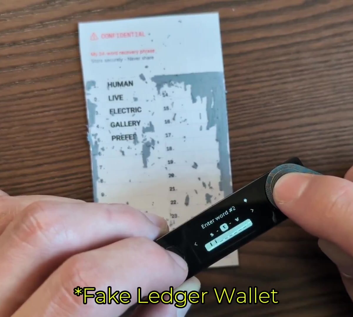 Hand bedient een namaak Ledger cryptowallet naast een kaart met herstelwoorden