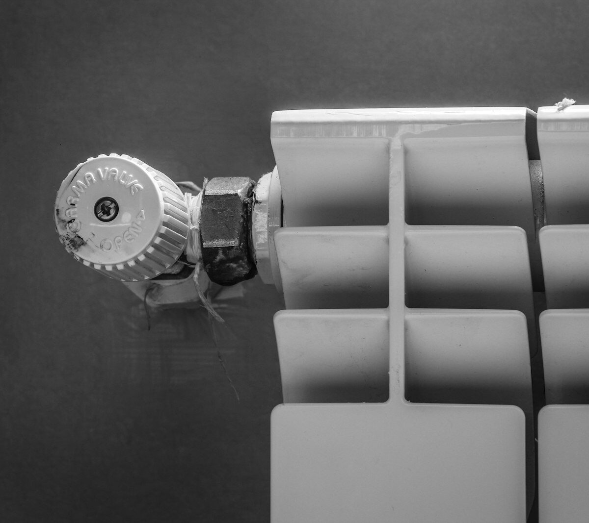 Hand die de thermostaatknop van een radiator lager draait