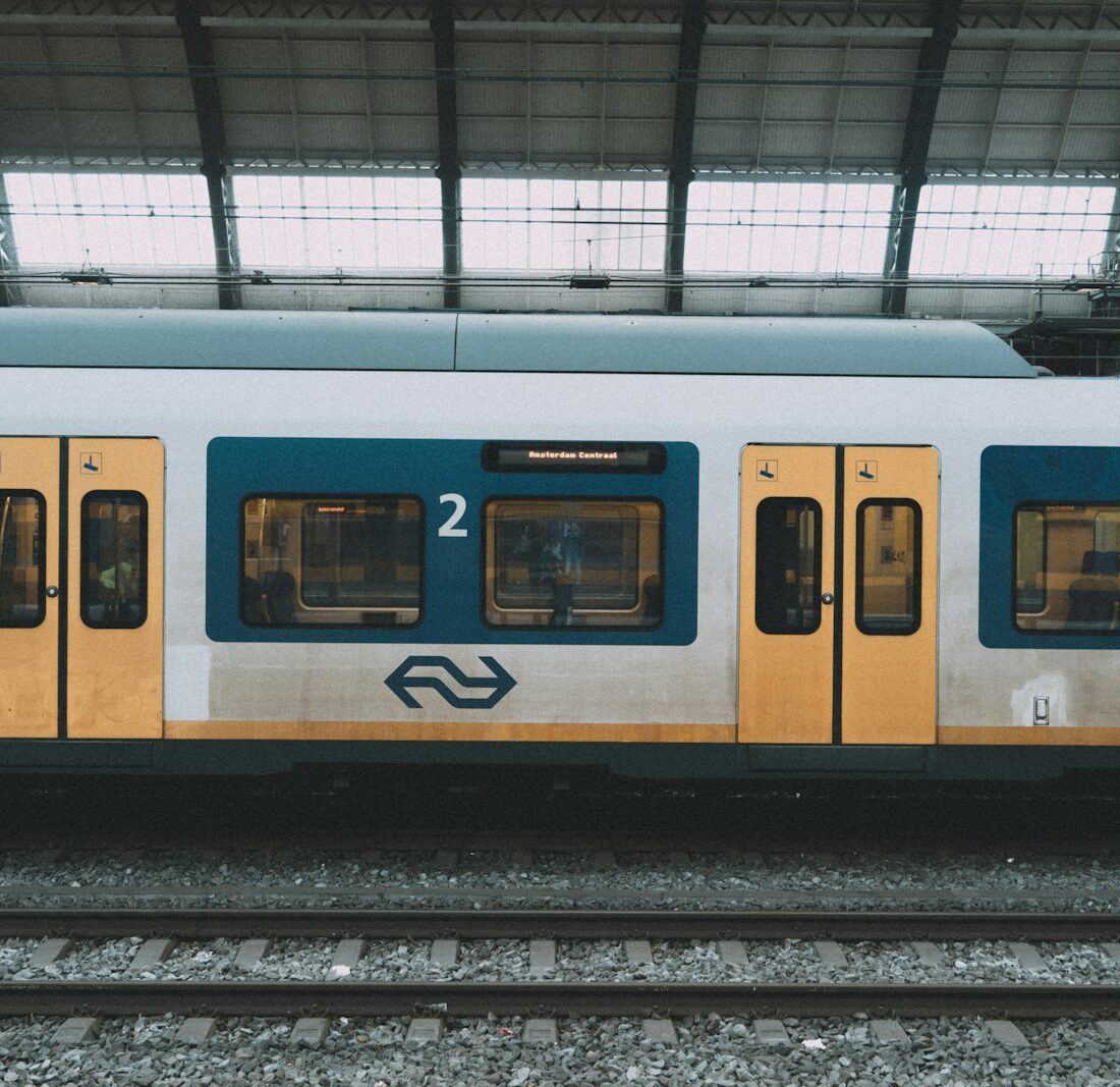 Gele NS-trein langs een perron op een Nederlands station