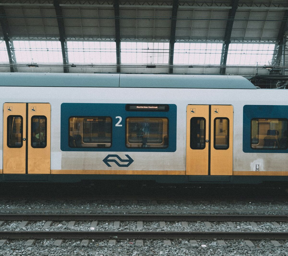 Gele NS-trein langs een perron op een Nederlands station