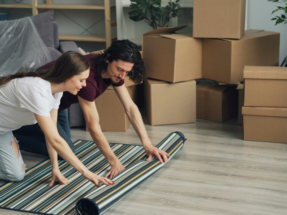 Jong stel draagt verhuisdozen hun eerste huis binnen