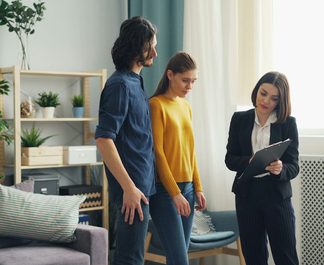 Makelaar geeft een jong stel een rondleiding in een lege woning
