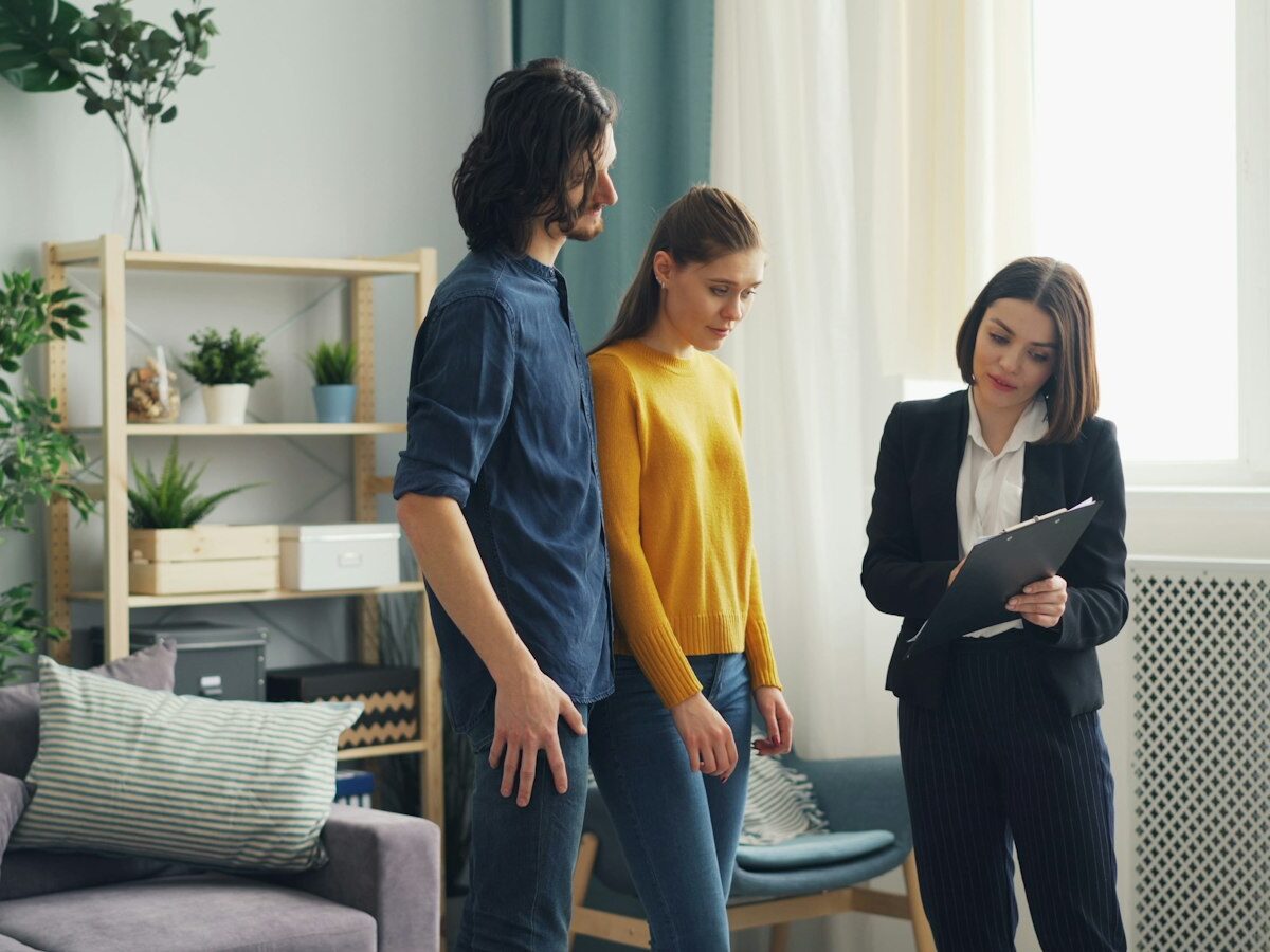 Makelaar geeft een jong stel een rondleiding in een lege woning