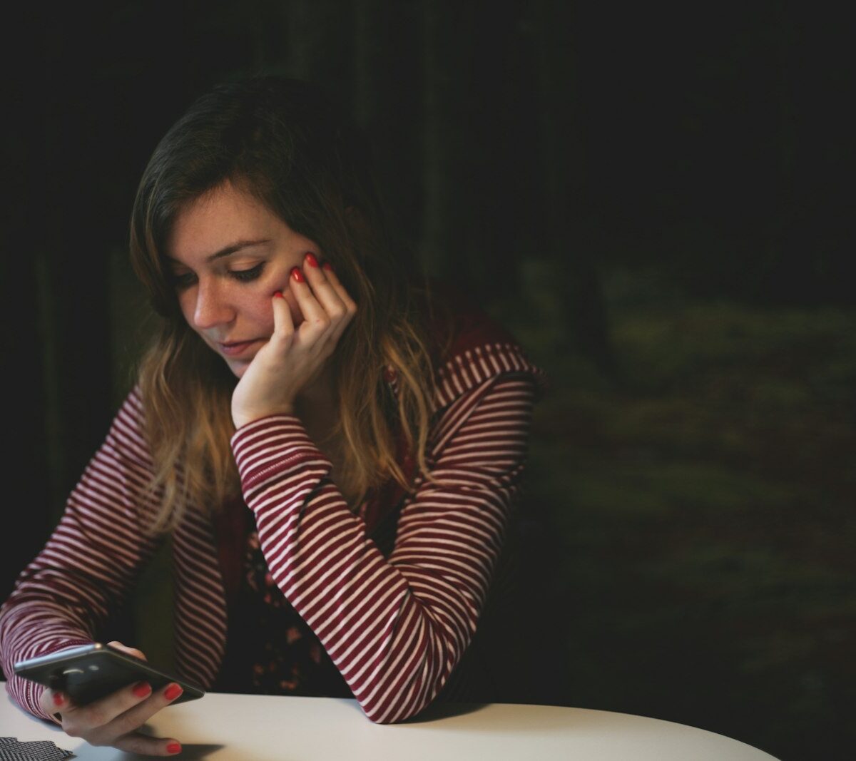 Jonge vrouw met verkoudheid op de bank met telefoon in de hand